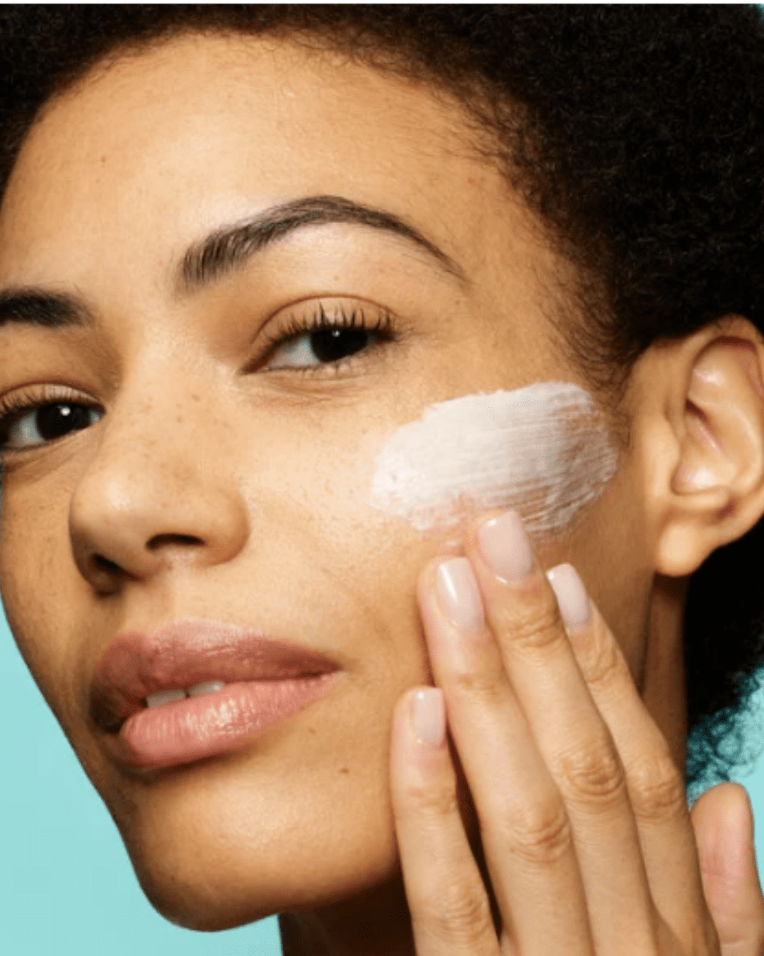 Cleanse & Polish™ Hot Cloth Cleanser being applied to a black woman's face on a teal background. Part of a September beauty guide.