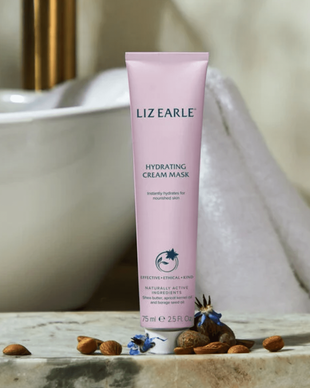 Liz Earle Hydrating Cream Mask on a bathroom counter in front of a white porcelain sink with a towel place over the edge of the sink. Part of a September beauty guide.