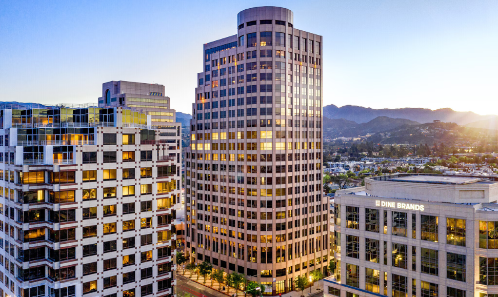 Algenist headquarters in Glendale, California, showing a tall industrial building with neighboring offices and mountains in the distance on a sunny day. The company where Algenist’s Liquid Skin Resurfacing 2% BHA Toner is created.