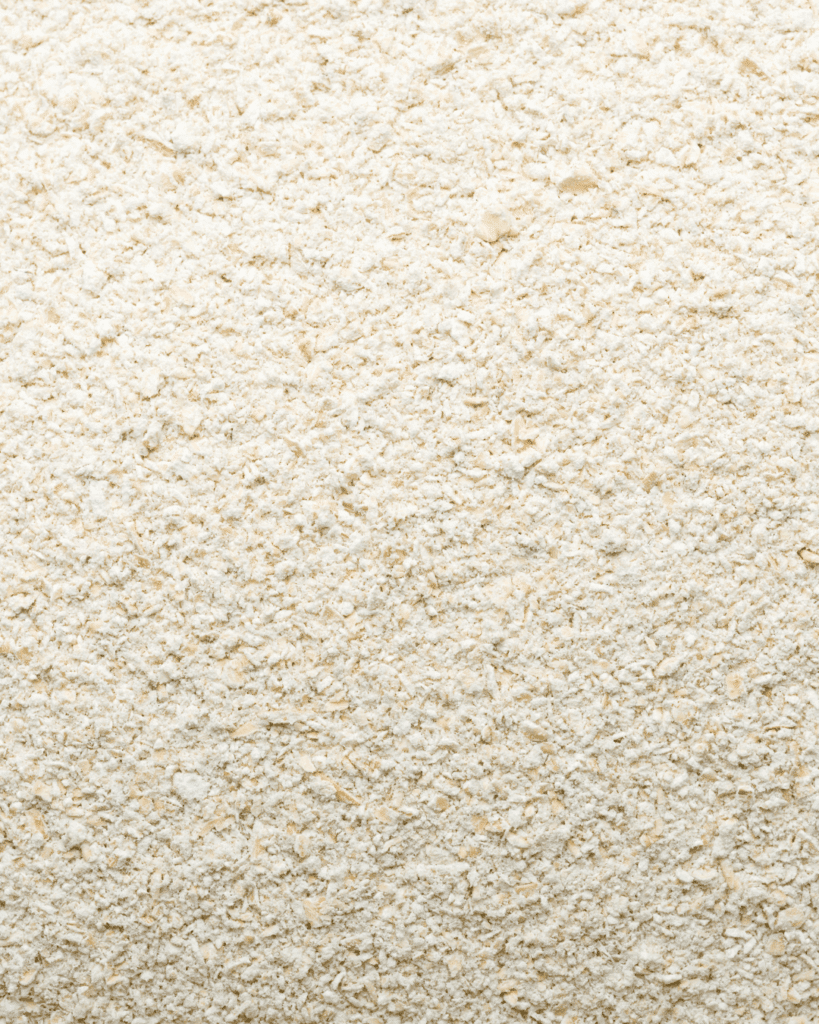 Close-up of organic oat flour on a neutral surface highlighting its natural, holistic skincare ingredient texture.