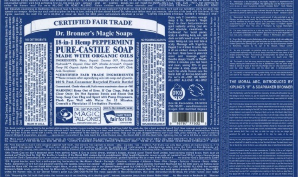 Flattened packaging from a soap product of Dr. Bronner's Peppermint Pure Castille Soap lad out to show the dense, small print text of Dr. Bronner and his philosophical writings across the label.