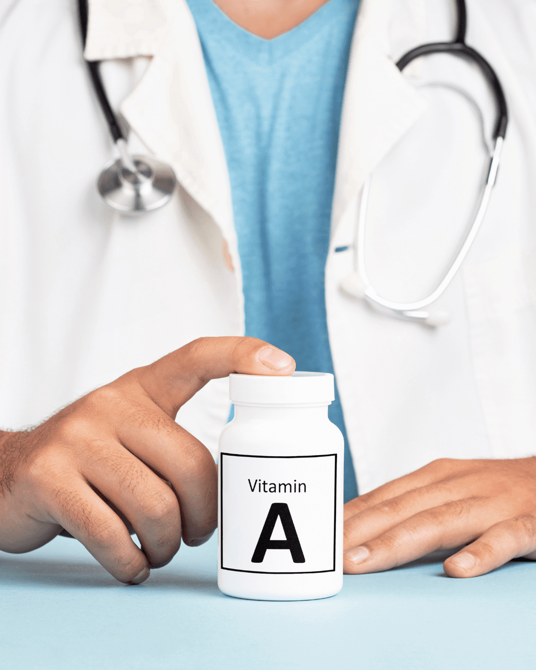 Doctor in a white coat and a stethoscope with his finger on top of a bottle that says vitamin A on it. An ingredient that can be found in Ayurvedic skincare and in this fall self-care guide.