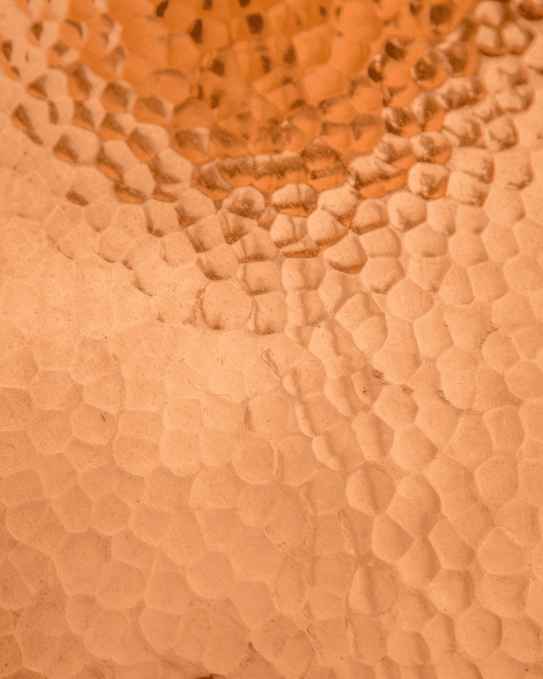 Copper, a key ingredient in the PRAI Beauty Necks=Generation Future Proof Night Cream, shown as a close-up of a textured Copper surface with small, patterned dents created a hammered effect.