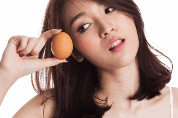 Asian woman holding an egg and looking at it