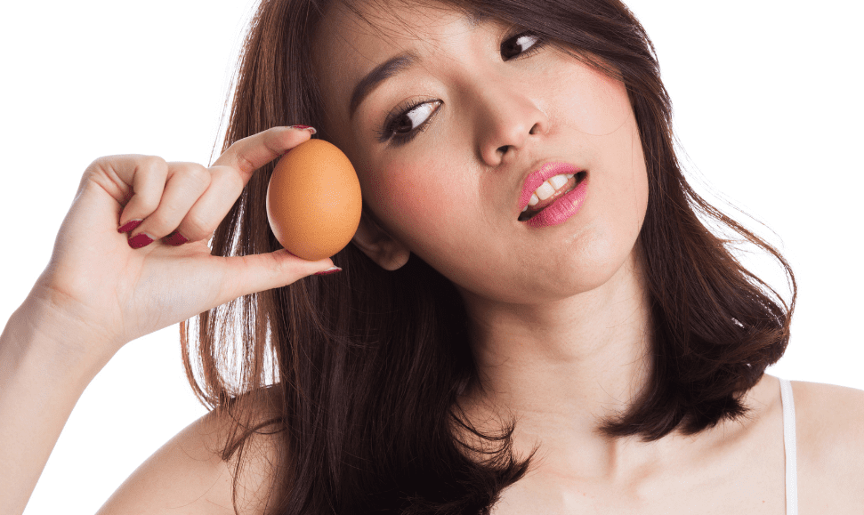 Asian woman holding an egg and looking at it