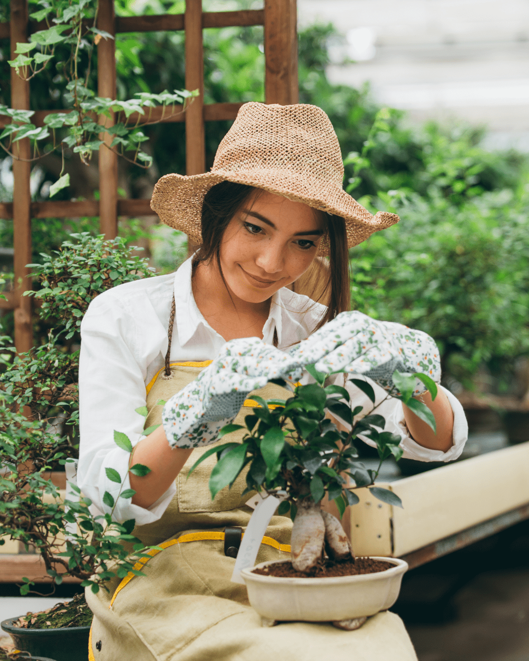 woman wearing a hat tending to a garden plant
