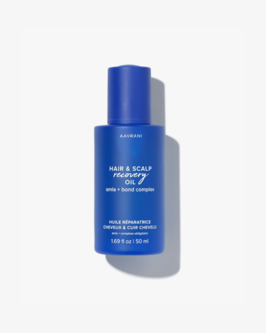 AAVRANI’s Hair & Scalp Recovery Oil in blue packaging, lying flat with a soft shadow against a white background.