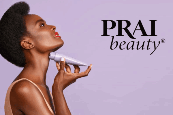 Black woman applying PRAI Beauty neck product to her neck, facing sideways and looking up, with a light purple background featuring the PRAI Beauty logo.