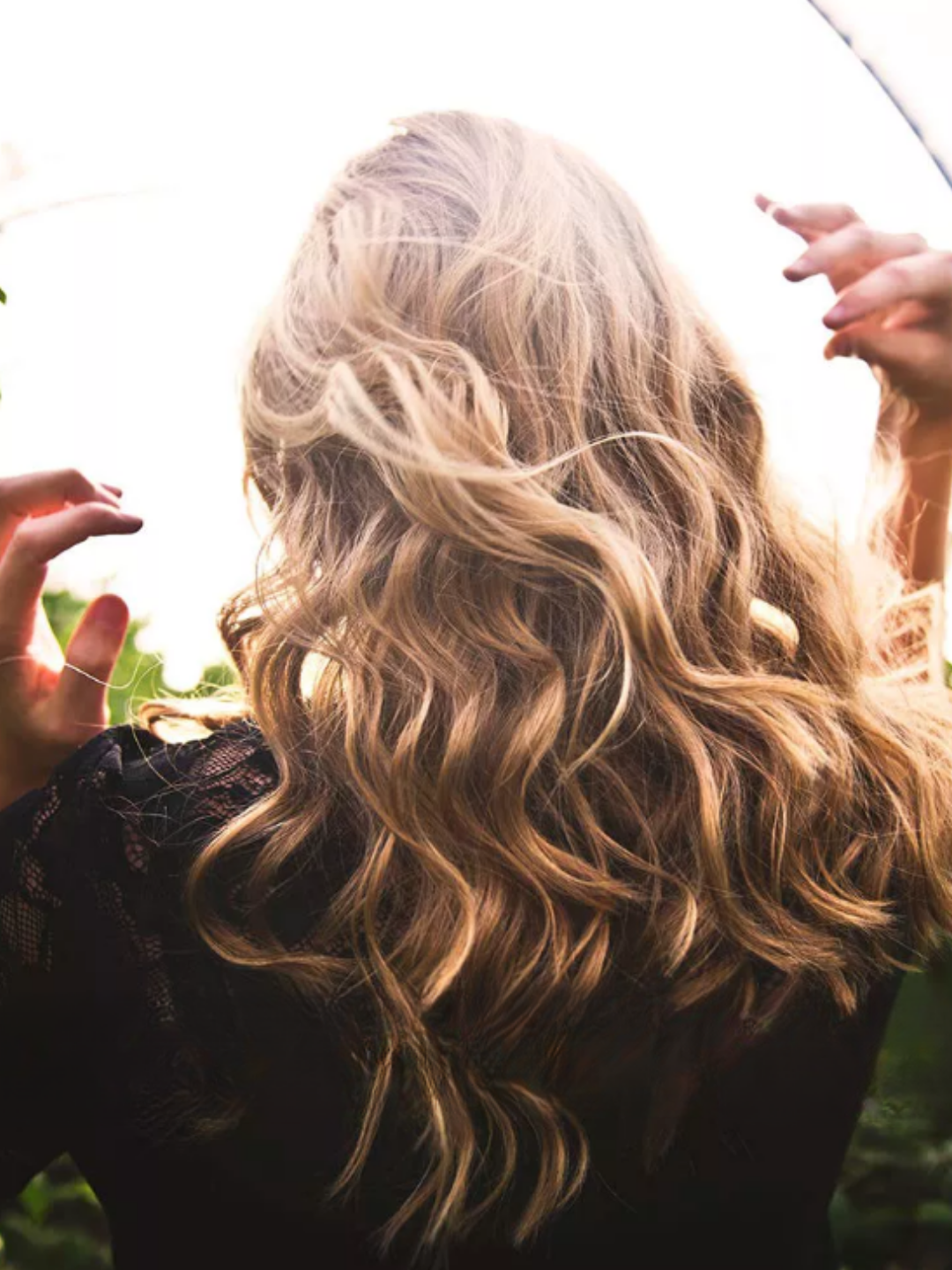 A woman outside with the sun shining on her hair, showing the healthy shine that Prell shampoo will give you.