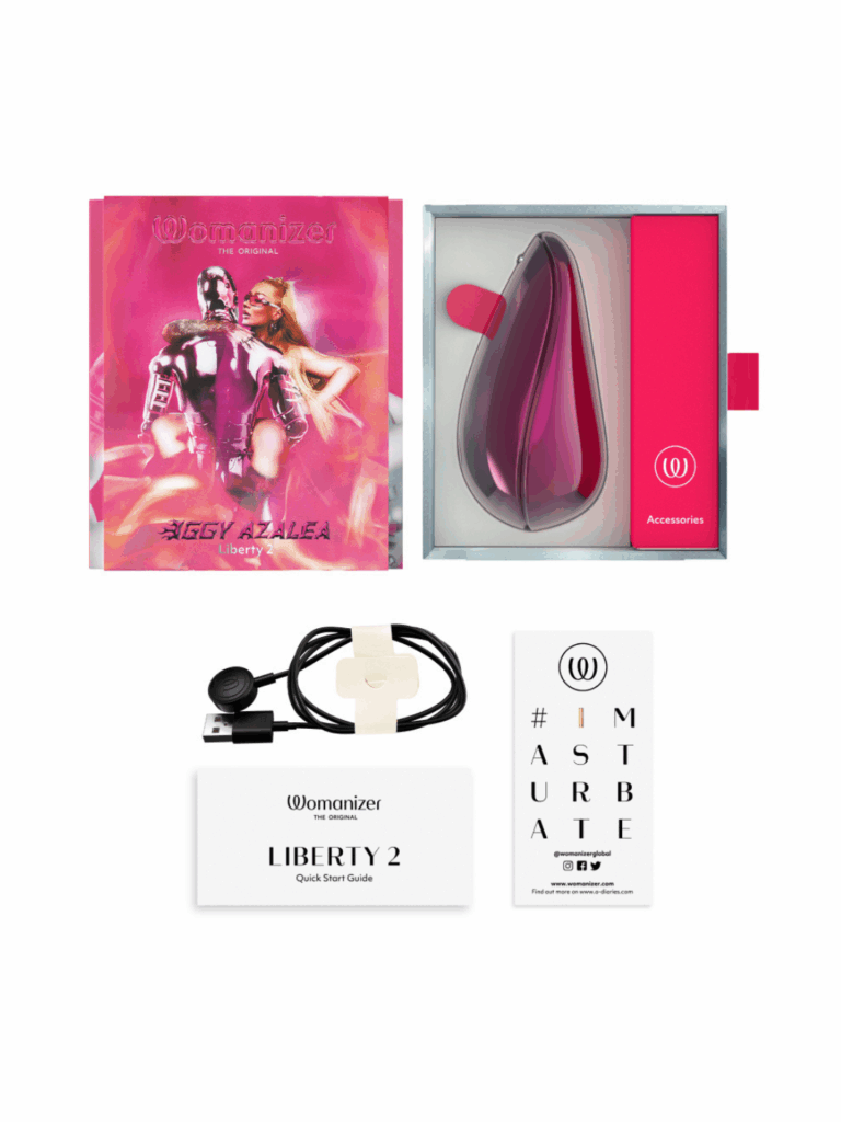 Full Womanizer and Iggy Azalea collaboration set displayed with box packaging boxes, charger, instruction manual, and a #imasturbate sticker. The metallic pink design symbolizes female empowerment, self-love, and luxury pleasure.