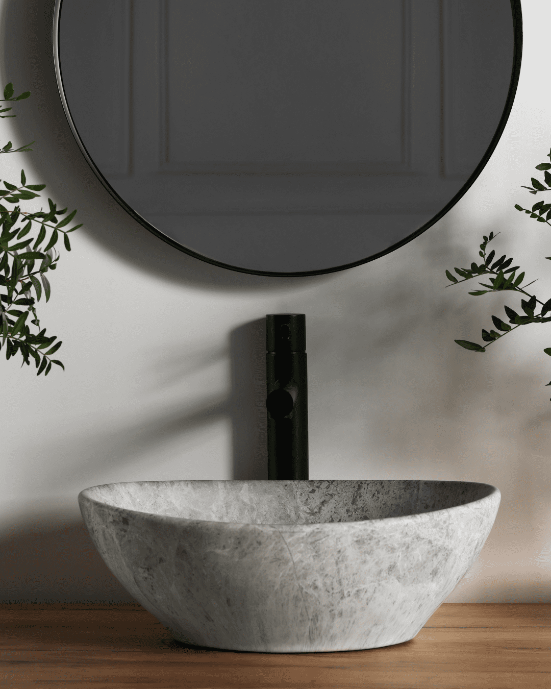 A modern bathroom sink beneath a circular mirror with plants and natural light, representing the clean, simple environment often associated with honey skin care rituals.