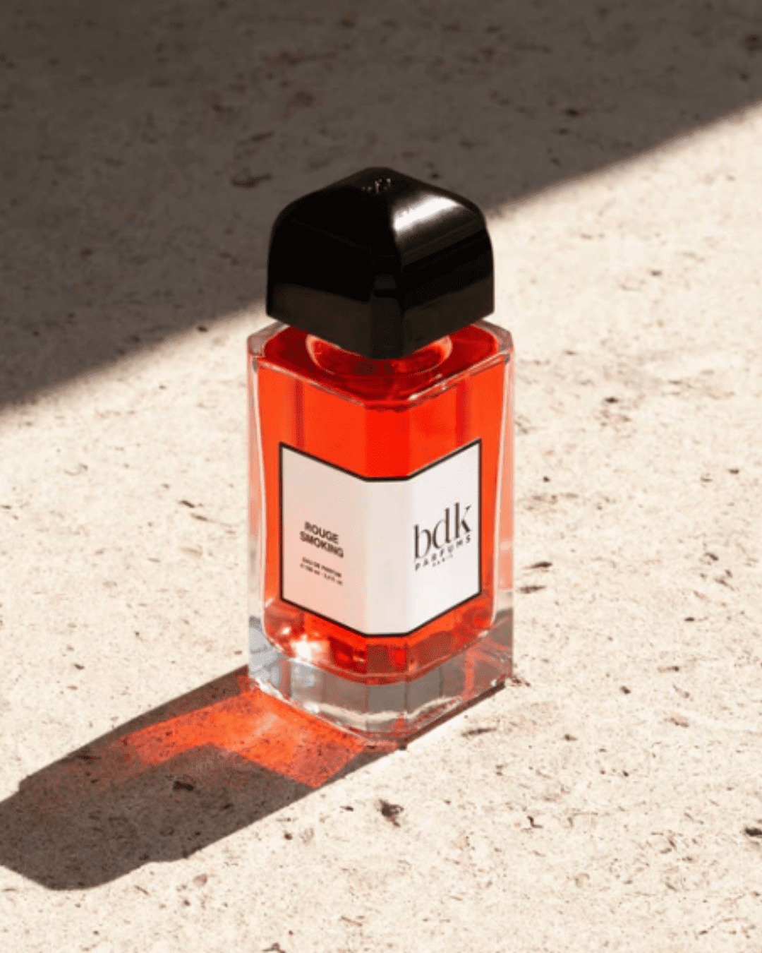 BDK Parfums Rouge Smoking Eau de Parfum on a stone surface with a shadow cast by the sun in this fall self-care guide.