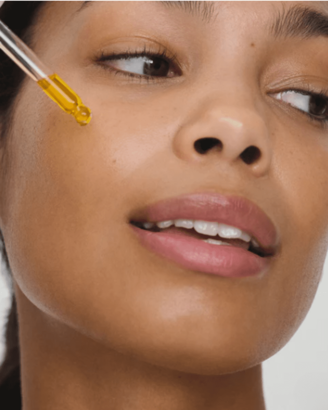 RMS Beauty Skincare Secrets Travel Kit serum being put on a woman's face. Part of the fall self-care & beauty guide.