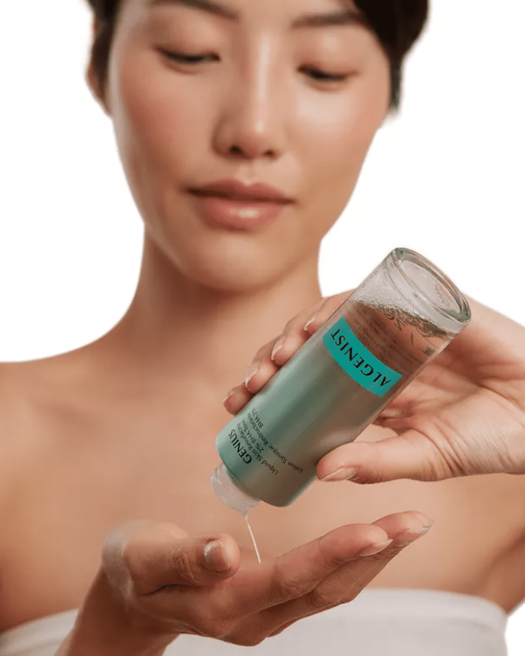 Asian woman in a white tub top pouring Algenist 2% BHA Toner into her hand against a white background.
