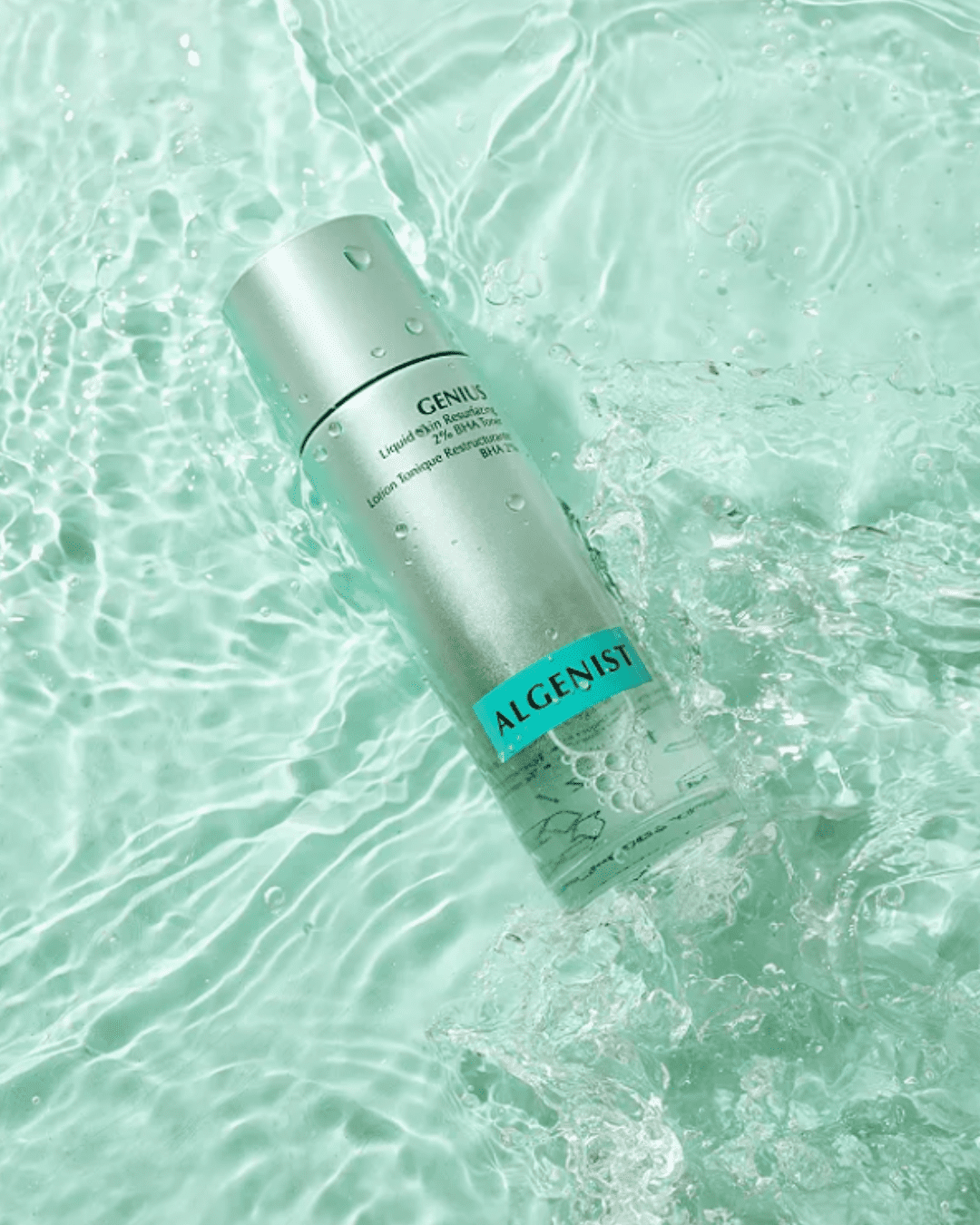Algenist’s Genius Liquid Skin Resurfacing 2% BHA Toner bottle resting on a watery teal surface.