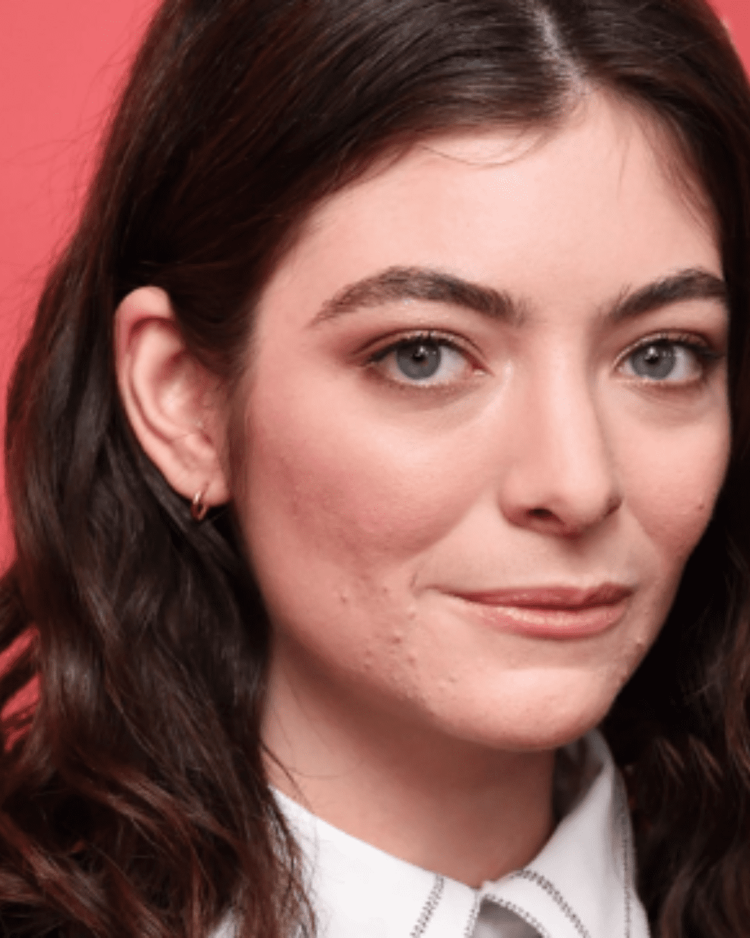 Lorde photographed at an event, her real skin shows acne and scars.