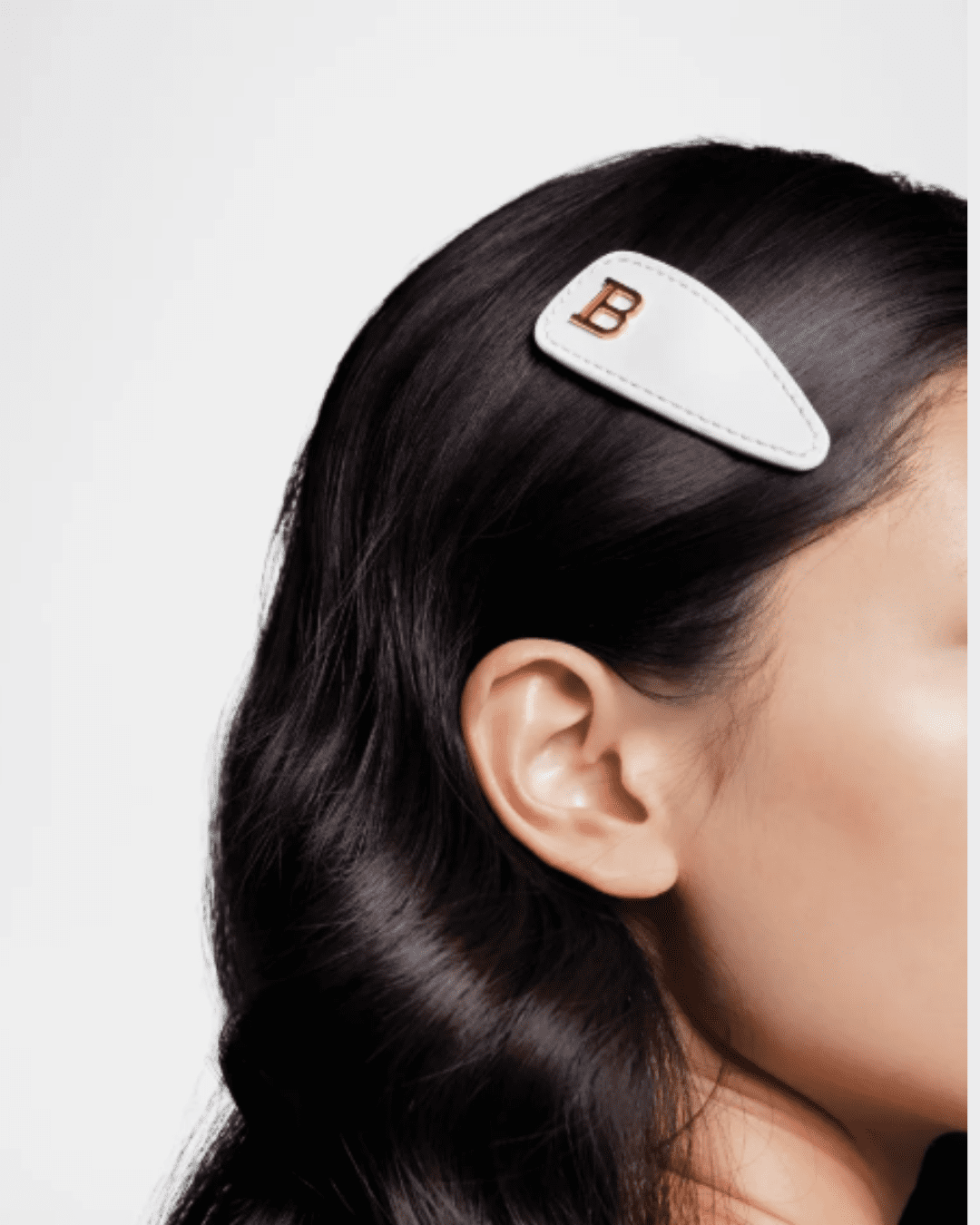 Balmain Hair Limited Edition Printemps Leather Snap Hair Clip worn by young woman with dark brown hair, securing strands stylishly.