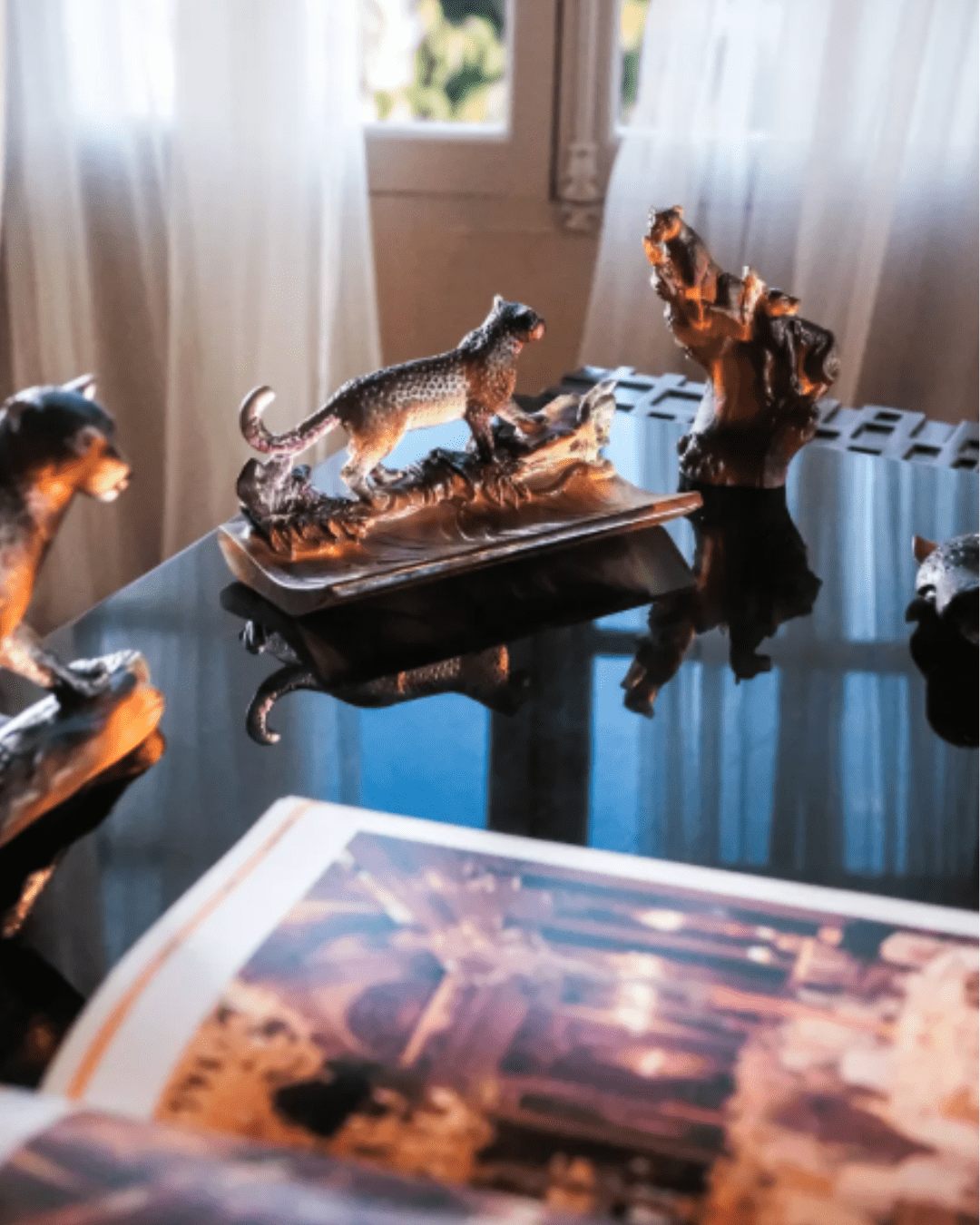 Daum Leopard Pen Holder placed on desk beside a coffee table book, wider view of office setting.