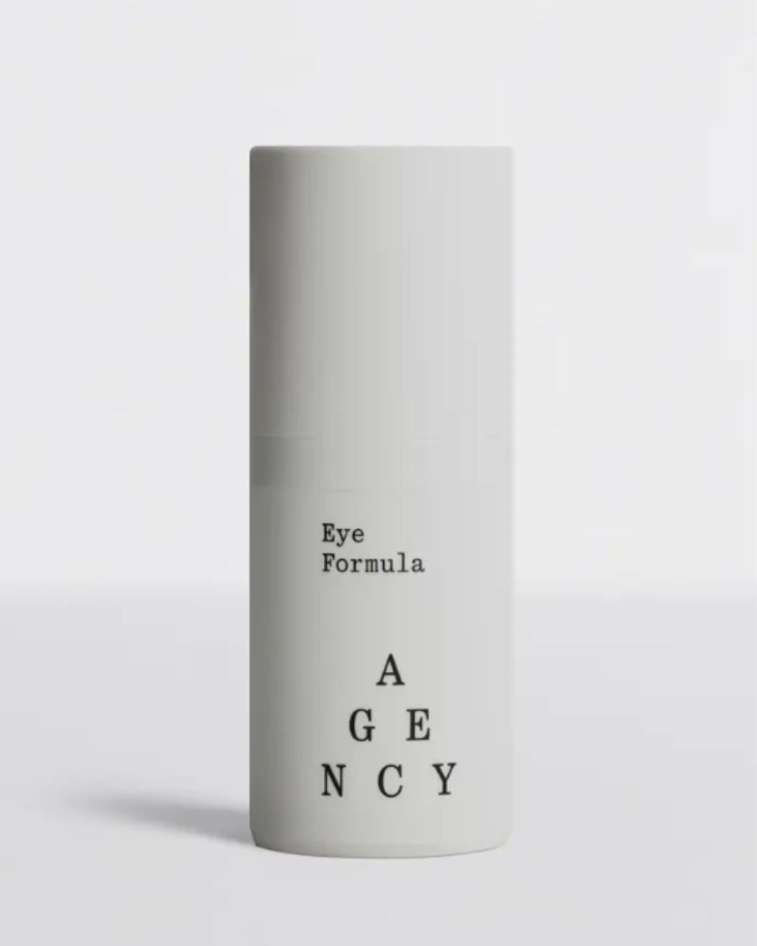 Agency Skincare Eye Formula anti-aging moisturizer in a gray bottle on a flat gray surface with a gray background, featuring "Eye Formula" in typewriter font and the Agency pyramid logo.