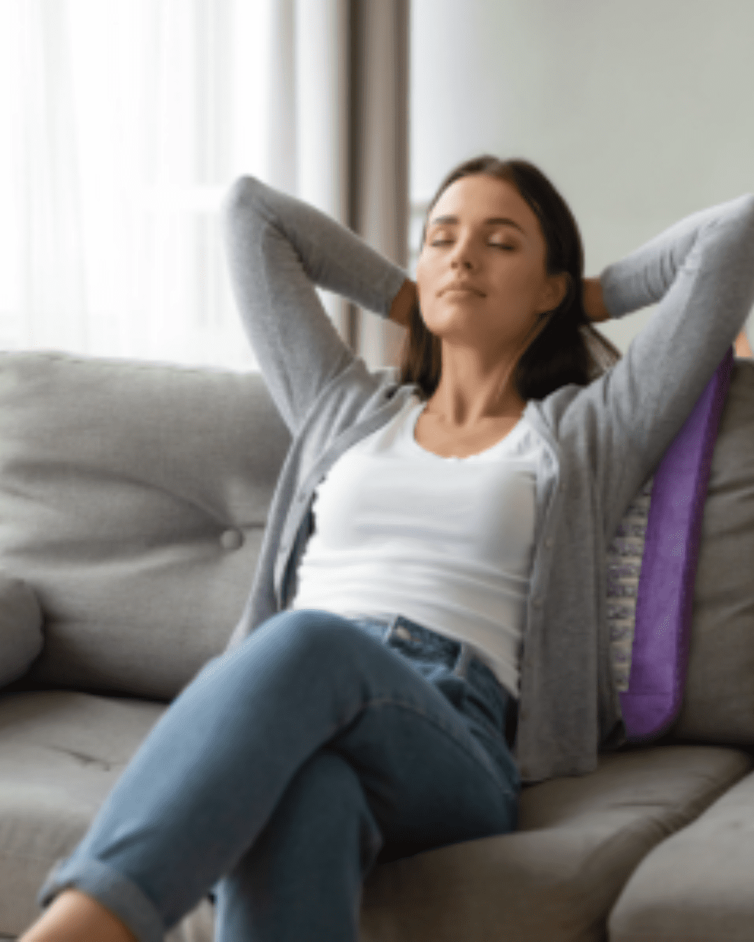 Woman reclining on couch on Sparkle mat for PEMF and red-light therapy, legs crossed, hands behind head.