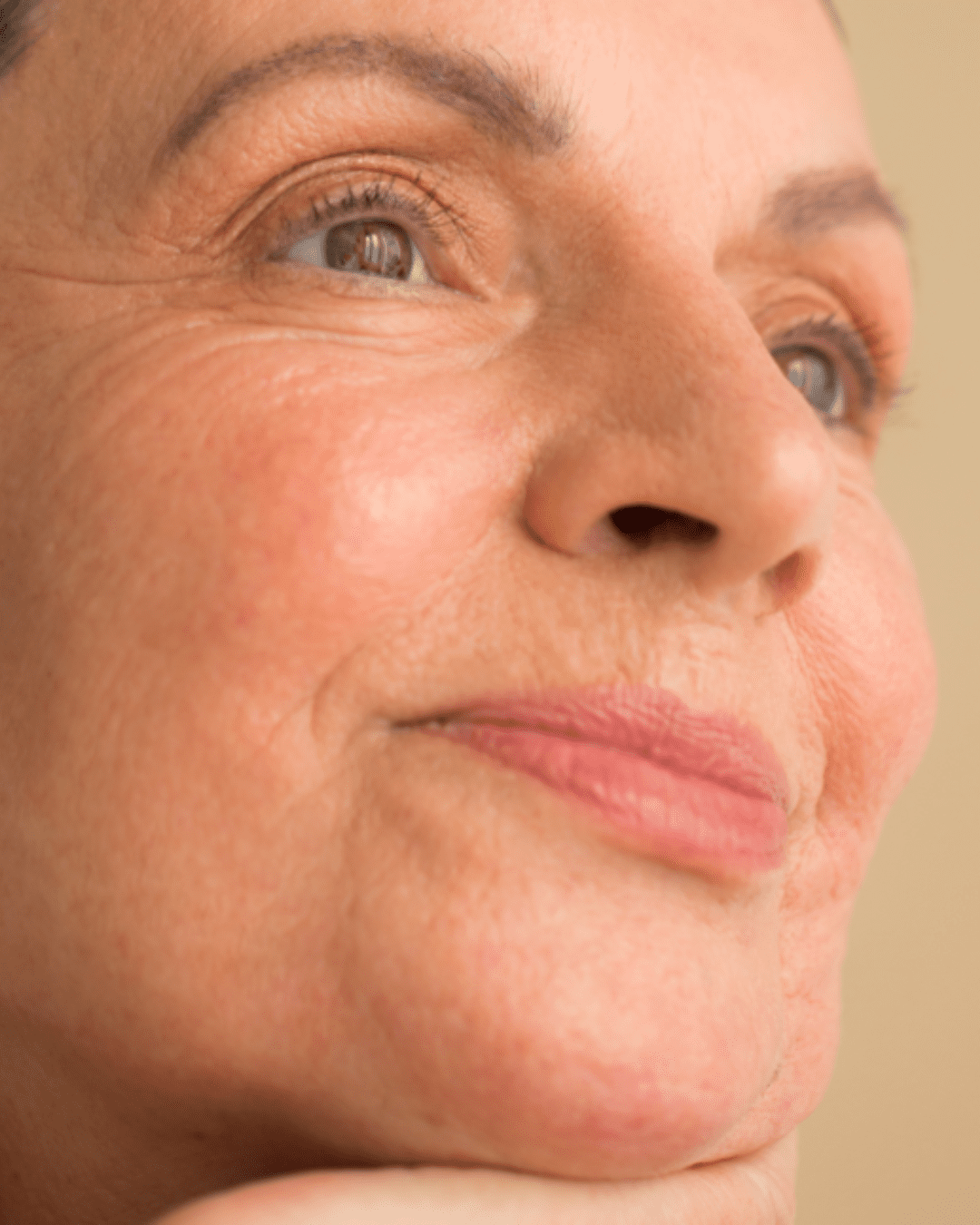 Close-up of a smiling white woman with light makeup, demonstrating healthy skin and radiance, highlighting the results of using anti-aging skincare.