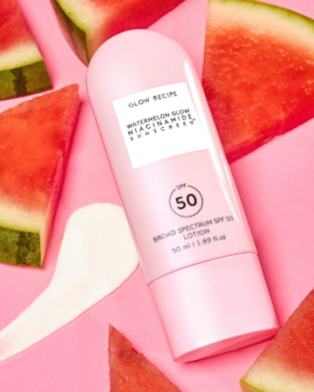 Glow Recipe Watermelon Glow Niacinamide Sunscreen SPF 50 on a pink surface with a swatch of the acne safe sunscreen and watermelon slices surrounding it.