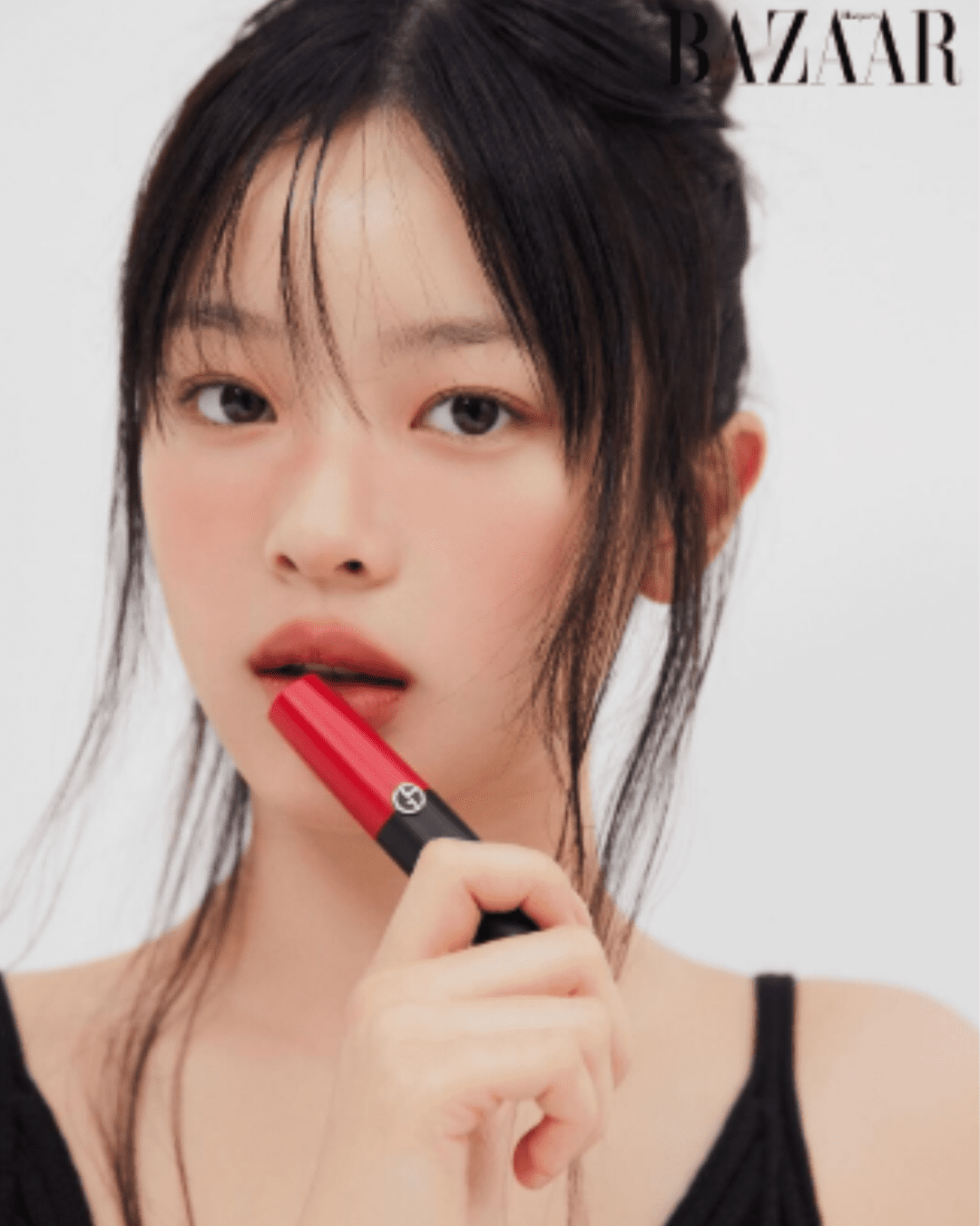 Hanni from New Jeans holding Giorgio Armani Lip Power Long-Lasting Matte Lipstick in shade 405-Power to her lips, showing color on lips.