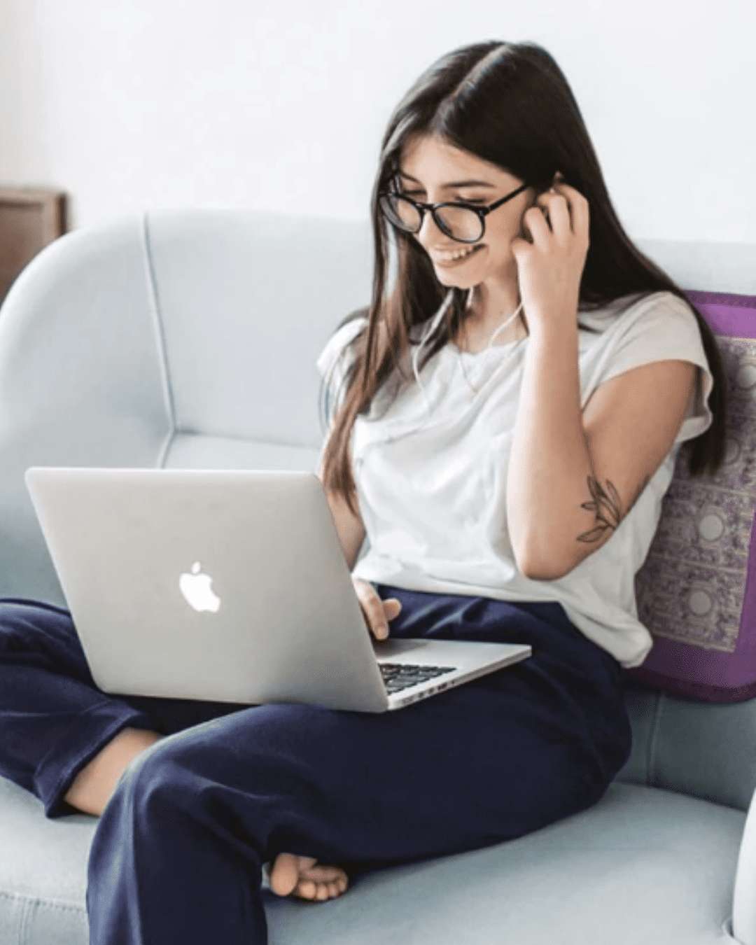 Woman sitting on couch with laptop using Sparkle Mat for PEMF and red-light therapy