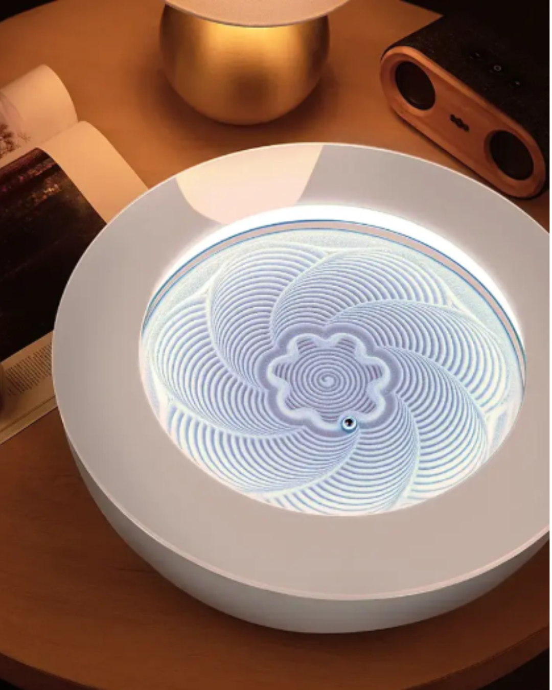 Close-up of HOMEDICS Drift Meditation Sand Table on a bedside table with open book and candle nearby, offering a calming space for a peaceful self-love practice.