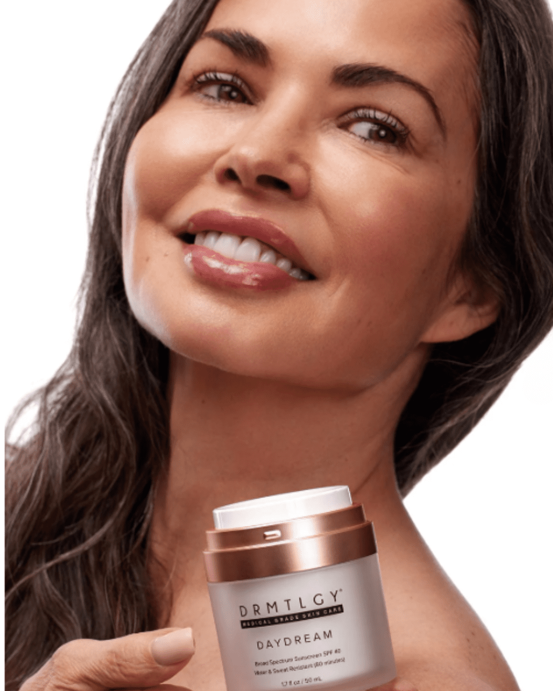 Mid-40s woman wiht brown skin and long brown hair setting DRMTLGY Daydream SPF 40 on her shoulder, looking off to the side, demonstrating sun protection on the body against a white background.