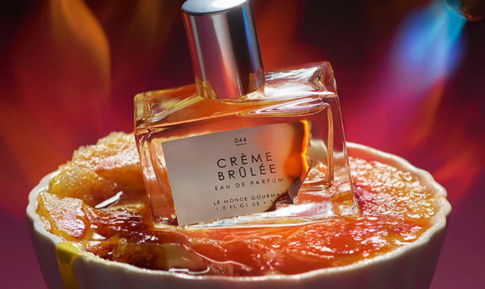Le Monde Gourmand Crème Brûlée Eau de Parfum bottle styled inside a white ceramic dish with Crème Brûlée and torch flames in the background, evoking gourmand sweetness.