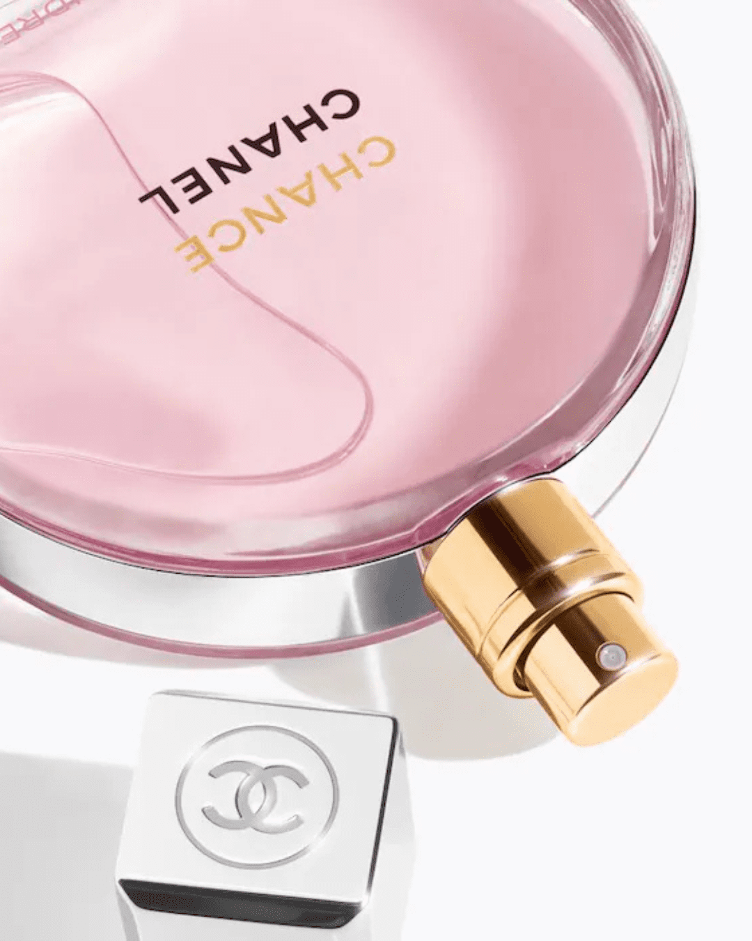 Close-up of Chanel Chance Eau Tendre upside down with cap off, showing silver Chanel logo, pink perfume, and gold sprayer, perfect for layering with ice cream perfumes.
