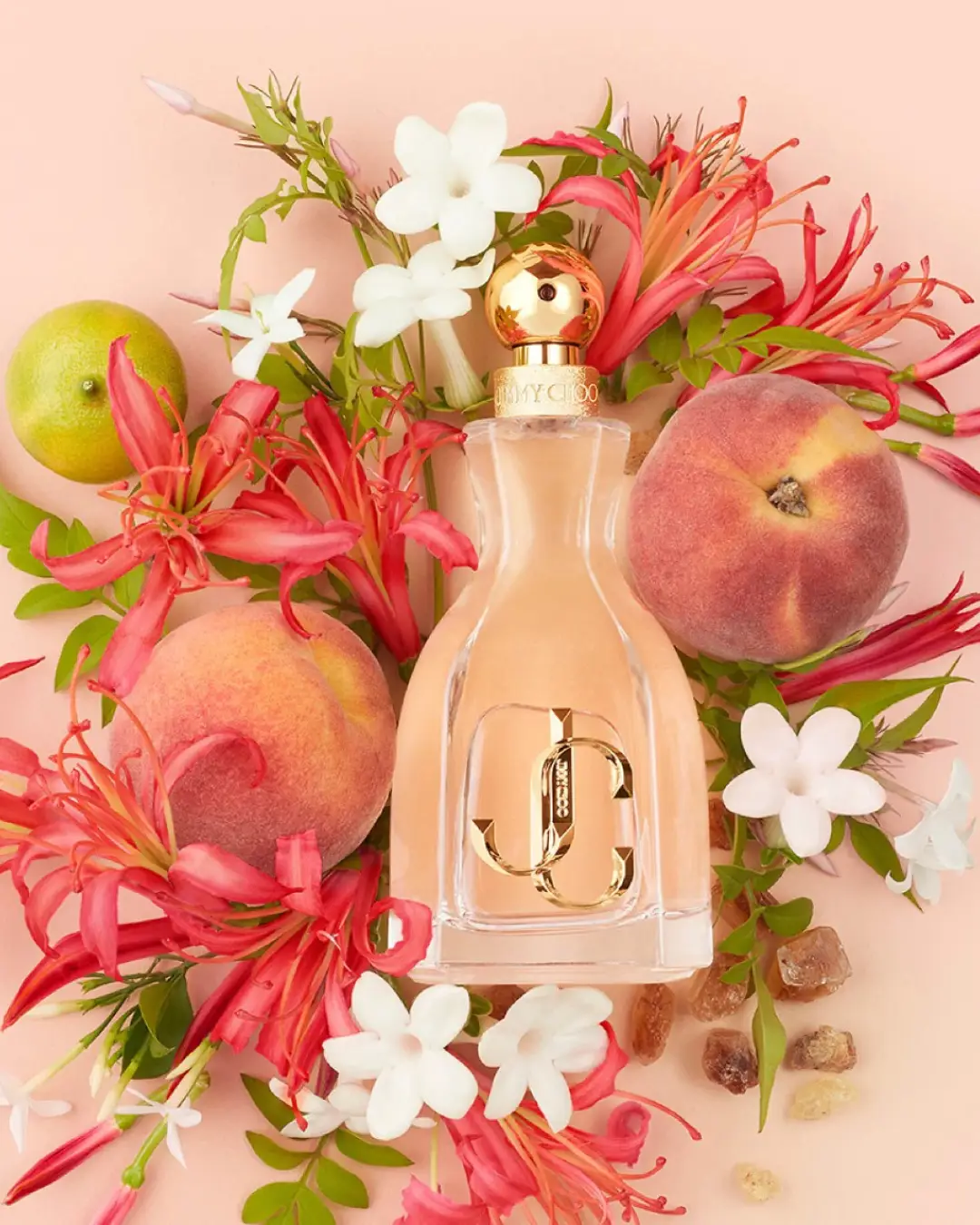 Jimmy Choo, I Want Choo Eau de Parfum styled with fresh peaches, lime, pink and white flowers on a soft peach-toned background, highlighting this peach perfume.