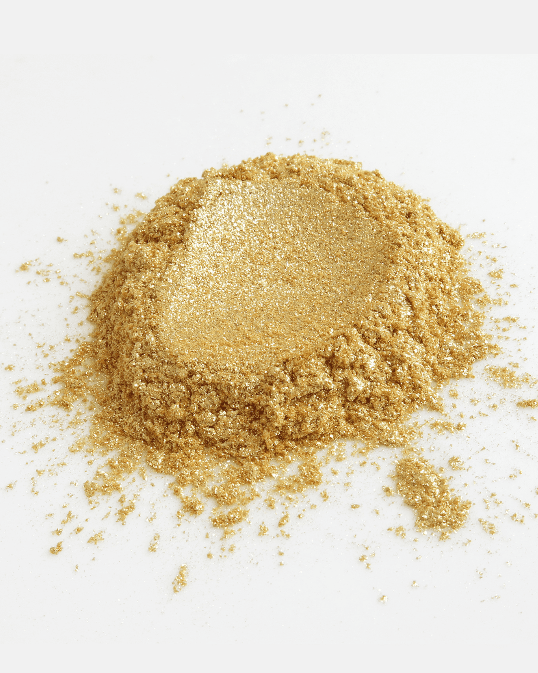 Gold powder with a circular imprint in the center on a white flat surface.