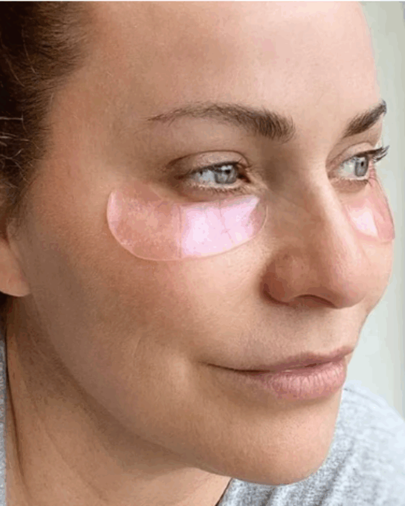 White woman gazing into the distance while wearing To Go Spa Rose Gold Under Eye Patches beneath her eyes.