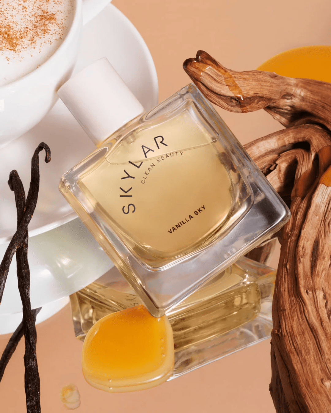 Vanilla Sky Parfum by Skylar Clean Beauty leaning against a coffee cup, vanilla beans, and caramelized cedar, highlighting this creamy ice cream perfume.