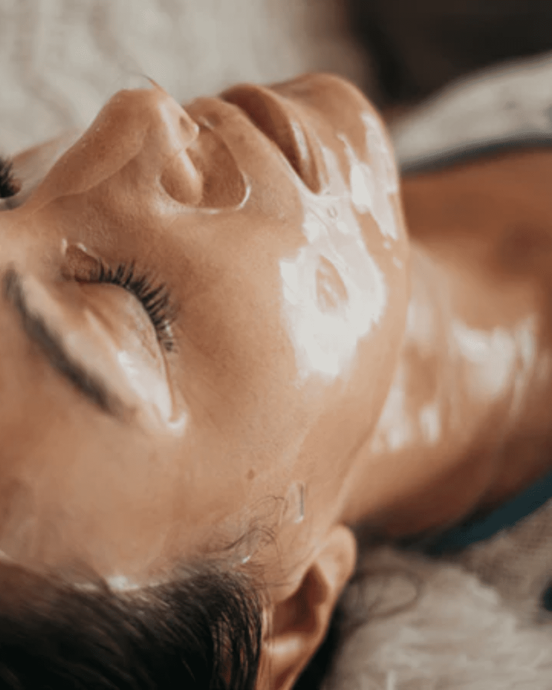 White woman lying down with eyes closed, wearing To Go Spa Face & Neck Collagen Hydrogel Mask, brown hair visible, relaxing.