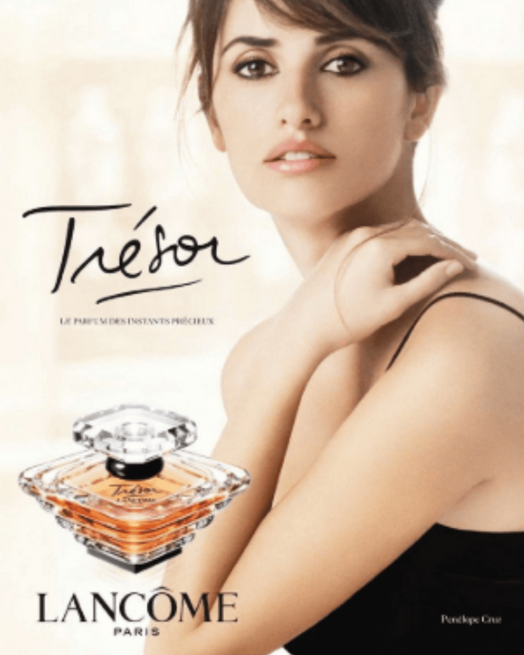 Penelope Cruz with her hand on her should next to the Trésor Eau de Parfum by LANCÔME bottle and tagline "fragrance for treasured moments", highlighting the peach perfume.