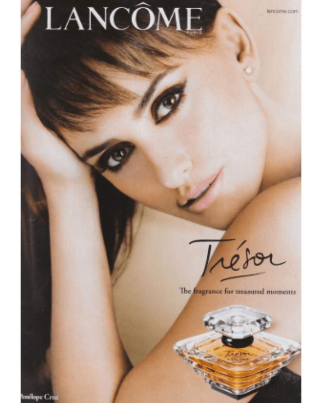 Penelope Cruz posing with her hand on her head beside Trésor Eau de Parfum by LANCÔME, a classic peach perfume, looking elegantly into the camera.