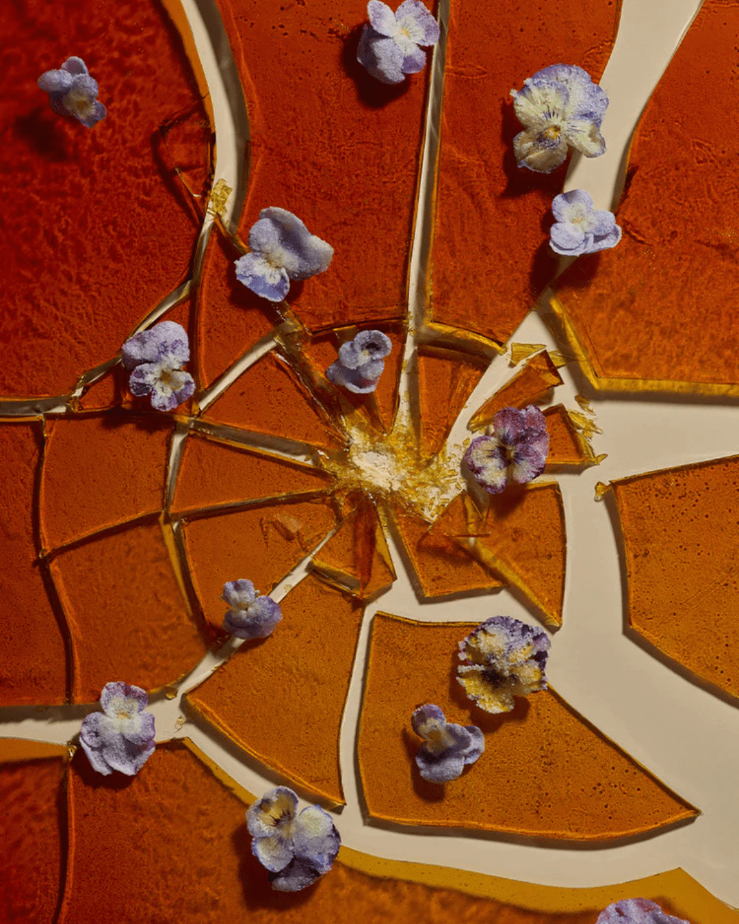 Close-up of the crystalized top of Crème Brûlée with purple flowers, reflecting the scent's gourmand notes.