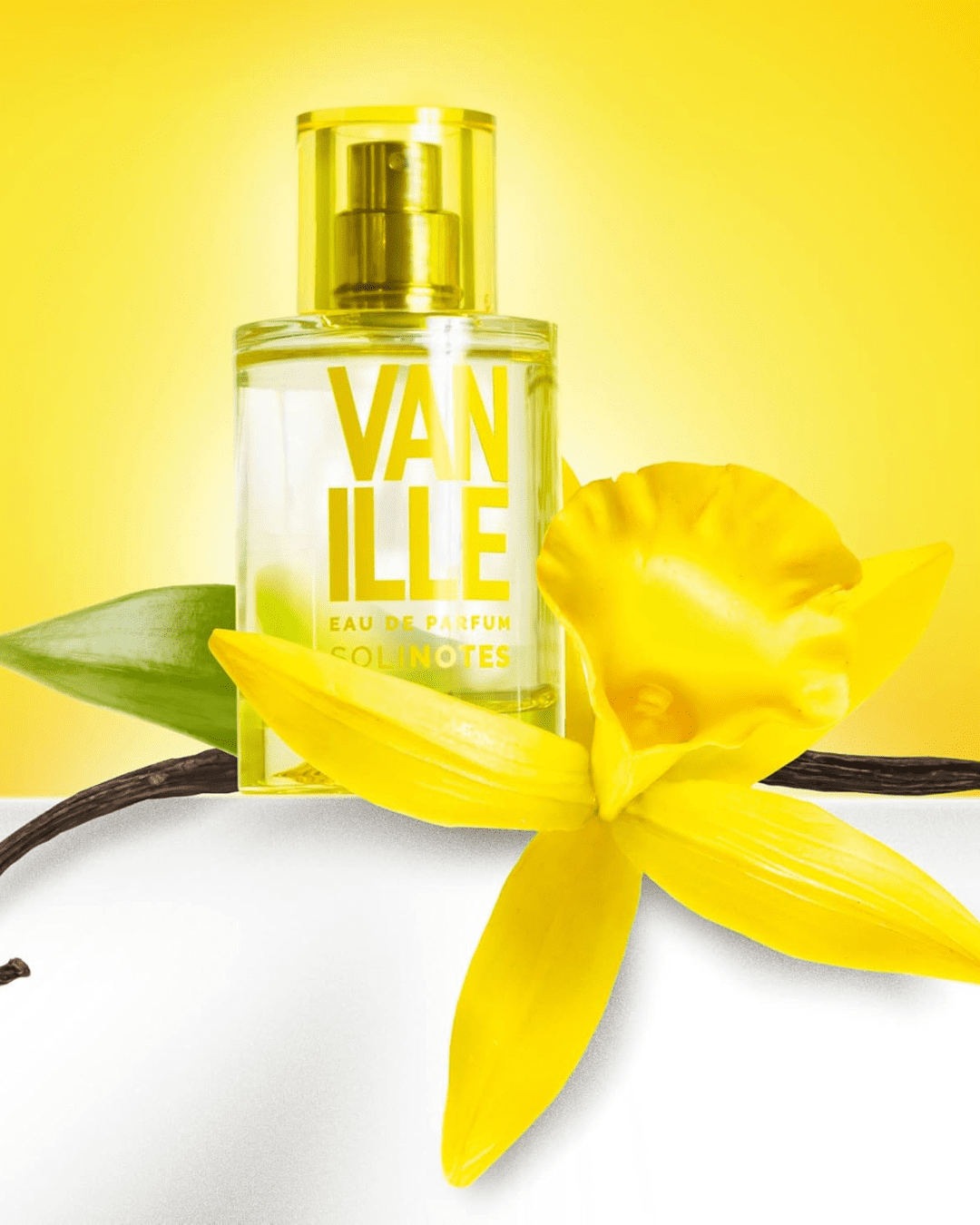Vanilla Eau de Parfum by SOLINOTES perfume bottle on a white stand with a yellow flower and vanilla beans, styled as one of the cupcake-inspired perfumes.