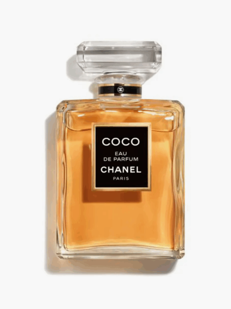 Coco Chanel perfume bottle lying flat on a white surface, showcasing its bright amber-gold fragrance inside the clear rectangular bottle.