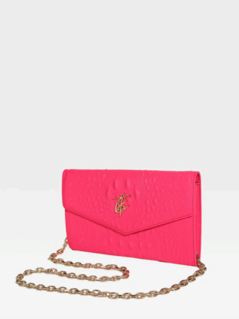 Front view of the neon pink Tote N Carry Statement Shoulder Purse on a white surface. The bag features gold hardware, a shoulder chain, and the gold Tote N Carry logo. Its structured interior offers space for a hand sanitizer and other daily essentials.