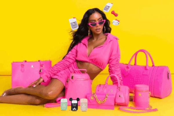 A stylish black woman poses on a neon yellow floor against a bright yellow background, dressed in a matching pink outfit and sunglasses. Around her are several pink vegan leather bags from Tote N Carry in different styles-a crocodile-print medium handbag, a pink backpack with front zipper and straps, a small gold-chained purse, an oval oblong handbag with a coin pouch, a circular upright purse, and a large pink carry-on travel bag. In front of the bags are colorful Touchland hand sanitizers, including green, Disney-themed with black Mickey ears, and a light pink one. Floating above her head are two Hello Kitty Touchland sanitizers featuring white and red designs with bows and cat ears.