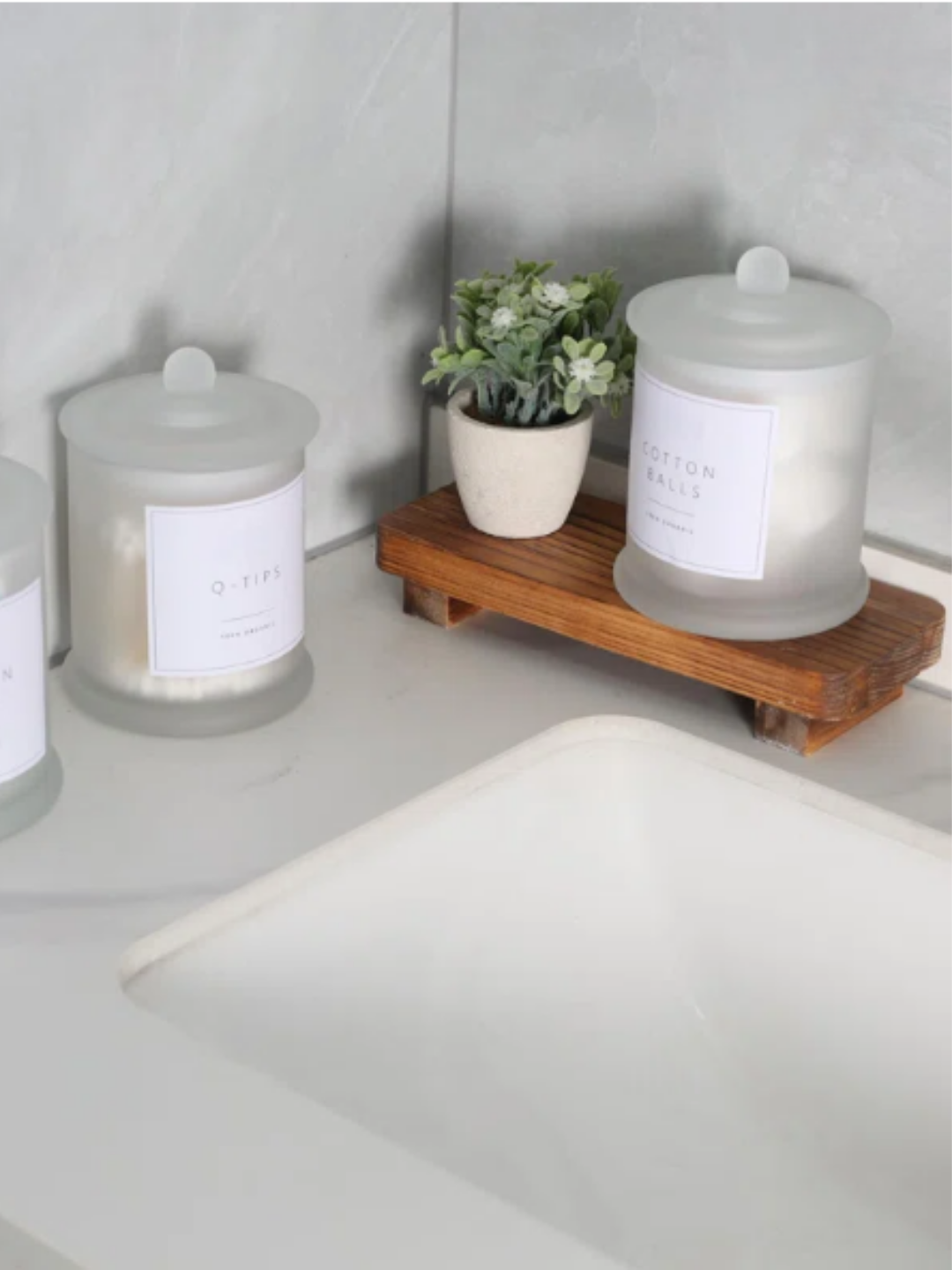 3 glass containers on the bathroom counter.
