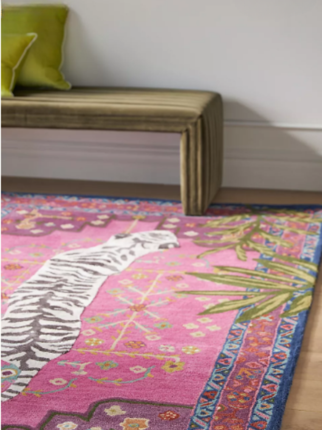 Pink Bengal tiger hand-tufted wool rug at an angle in sunlight, styled with a fabric covered bench with green pillows to show texture and soft tones in a living space.