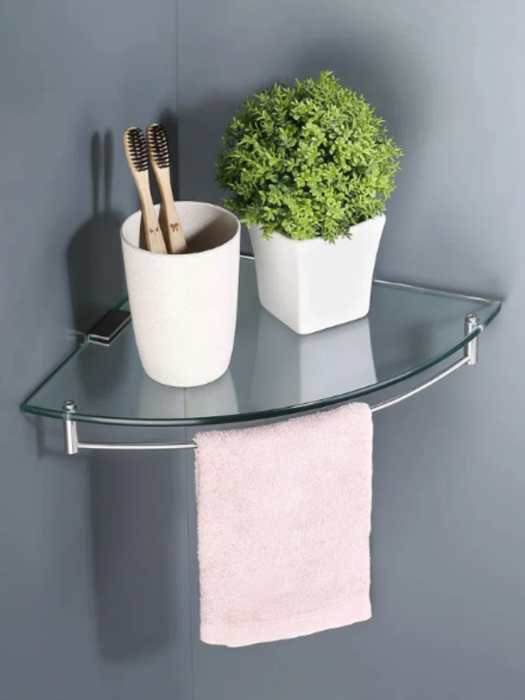 A small glass corner shelf with a towel hanger on the bottom.