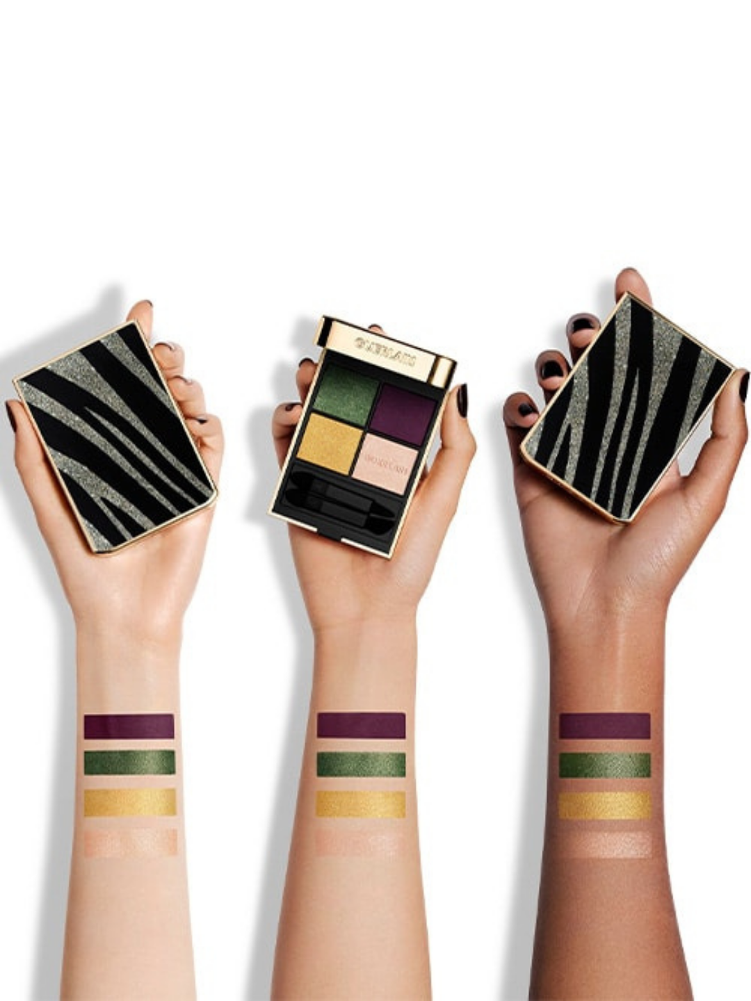 Guerlain G879 glittery Tiger eyeshadow palette from the 2023 holiday collection shown with wrist swatches on light, medium, and dark skin tones. The light skinned and dark-skinned hands are holding closed cases while the medium skin tone is holding an open eyeshadow pallet so you can see the inside.