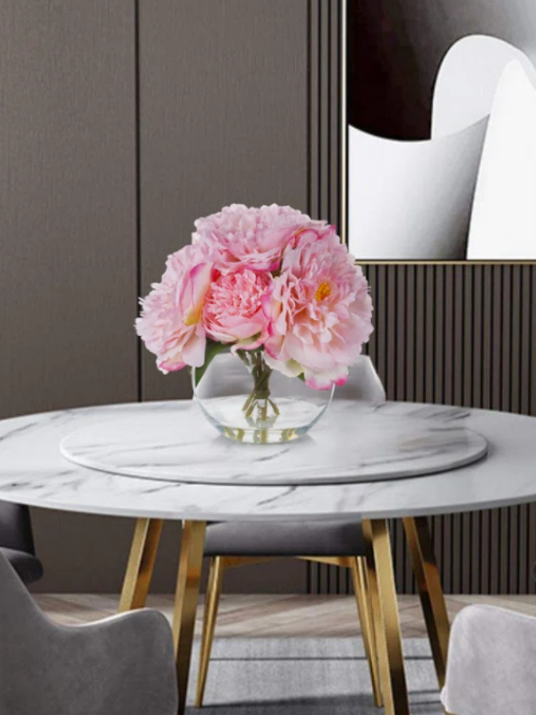 Pink peonies in a glass vase on a white marble table.