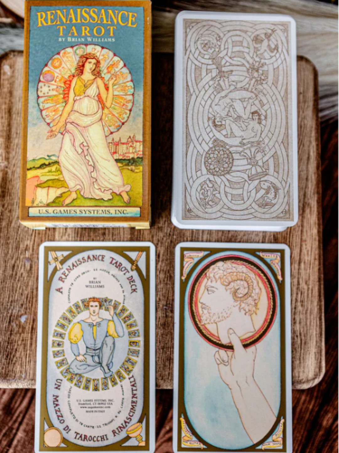 Image of the Renaissance Tarot box top, the card-back design with intertwined male and female figures in a yin-yang pose framed by Celtic knotwork, and two sample cards. The warm gold earthy tones echo the early-summer atmosphere associated with the Strawberry Moon, giving the deck a soft, seasonal richness.